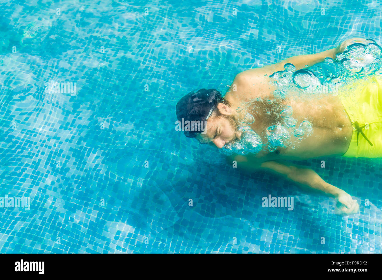 Top view of a young man floating underwater in a swimming pool Stock Photo