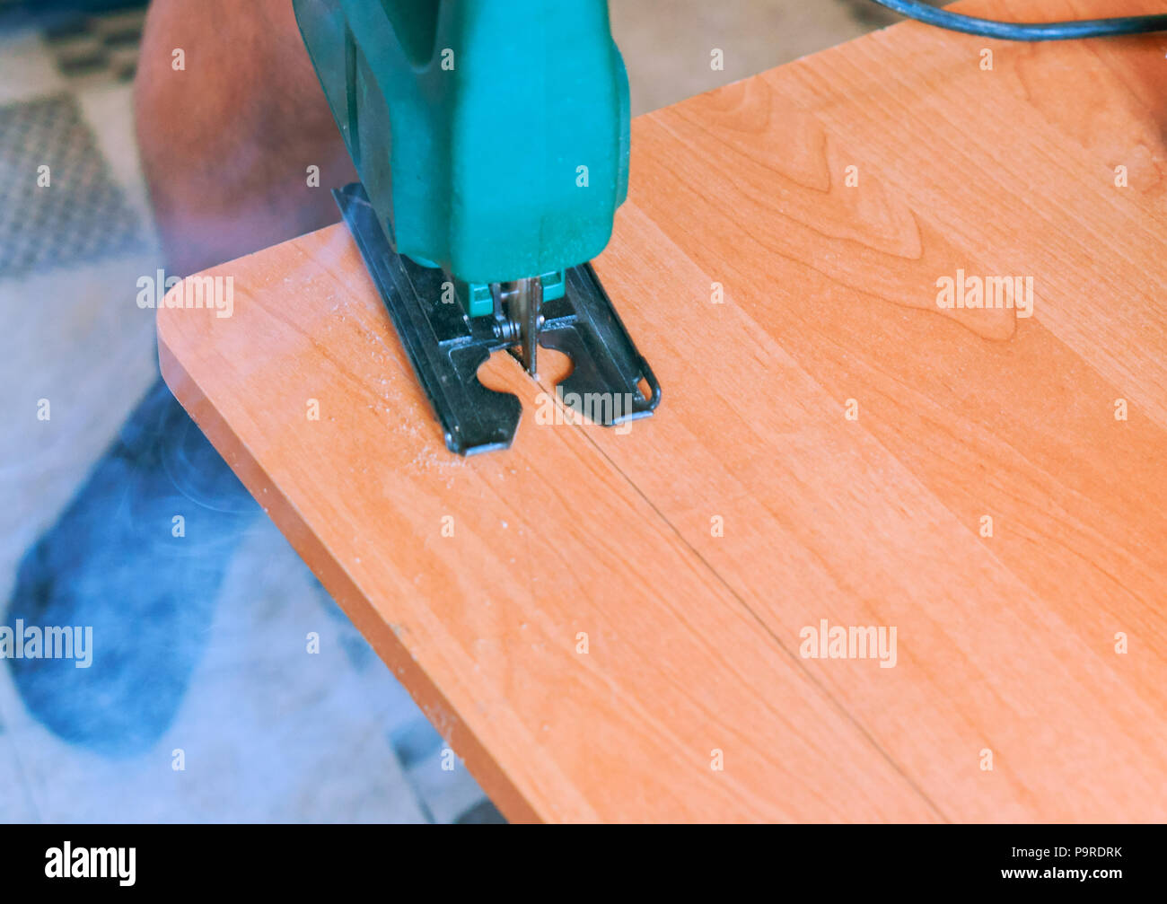 man works as a jigsaw on a tree, a carpenter with a cutting tool Stock