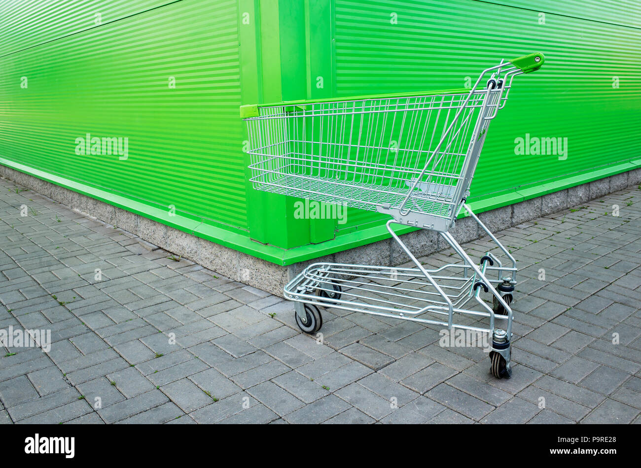 Empty shopping cart parking on green background with copyspace. retail store. Stock Photo