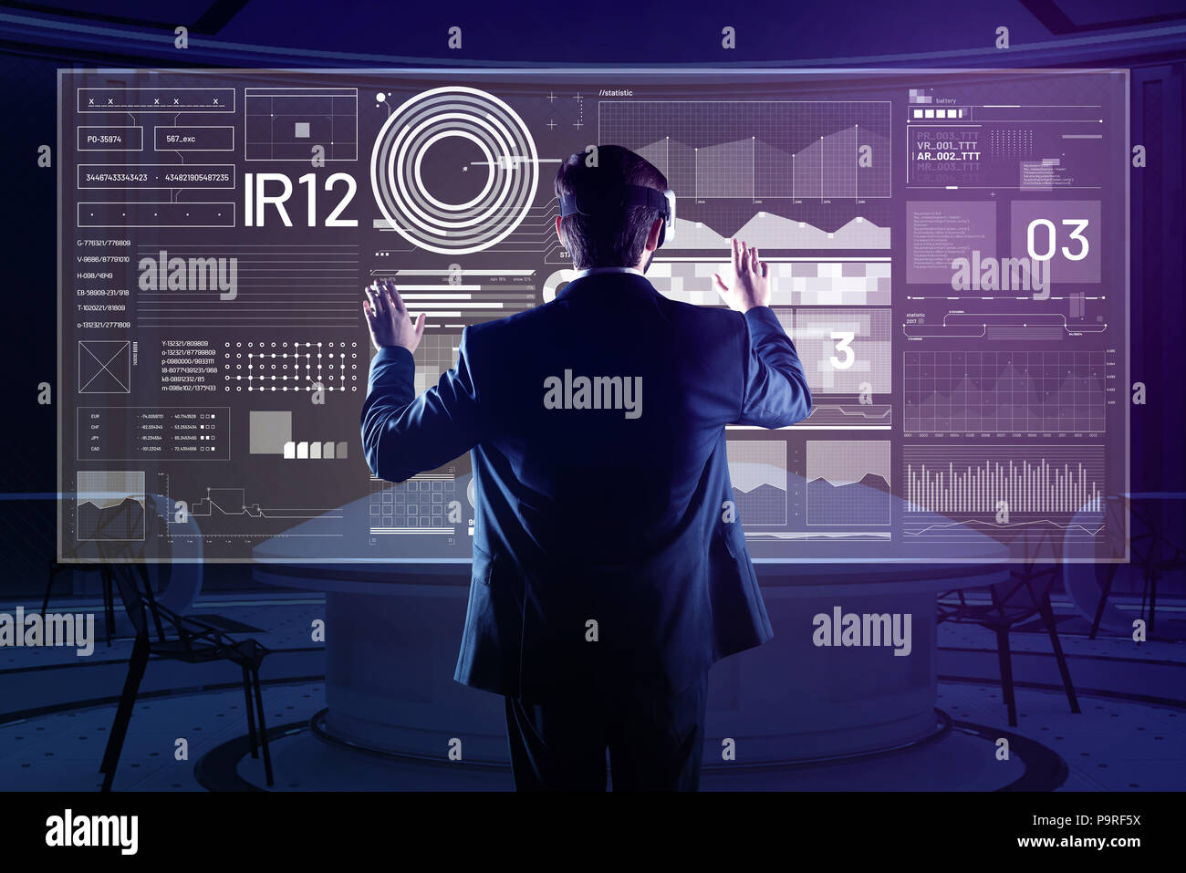 Scanning new information. Attentive software developer using modern virtual reality glasses while being in his comfortable office and analyzing the in Stock Photo