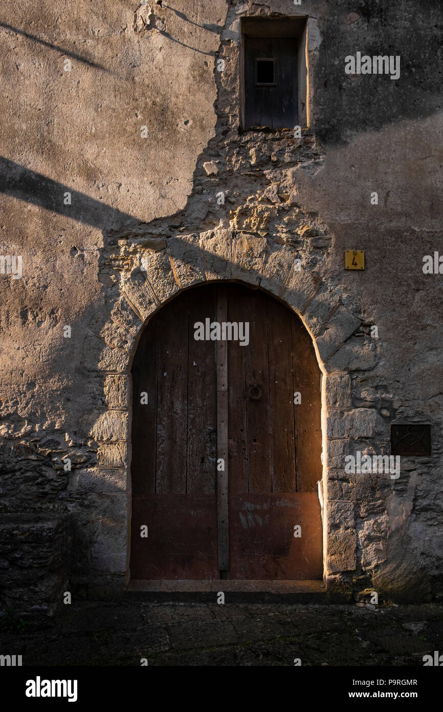 Early morning sunlight glancing across an arched doorway in an old building, Beget, Catalonia, Spain Stock Photo