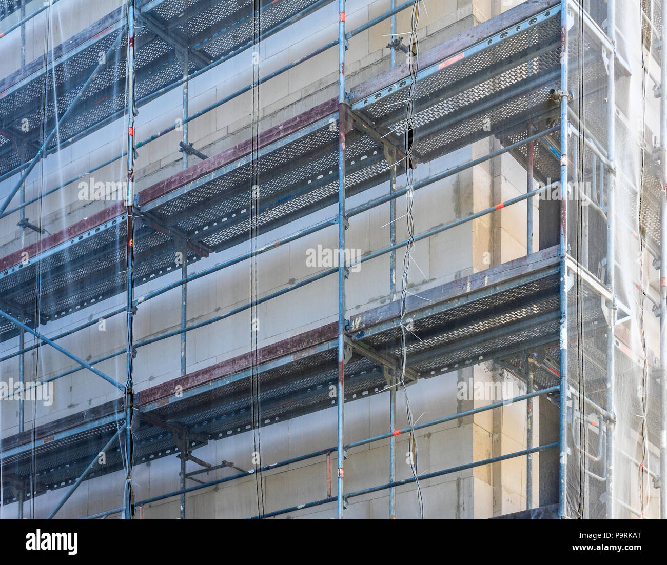 Scaffolding on the shell of a large new building, with a net to protect