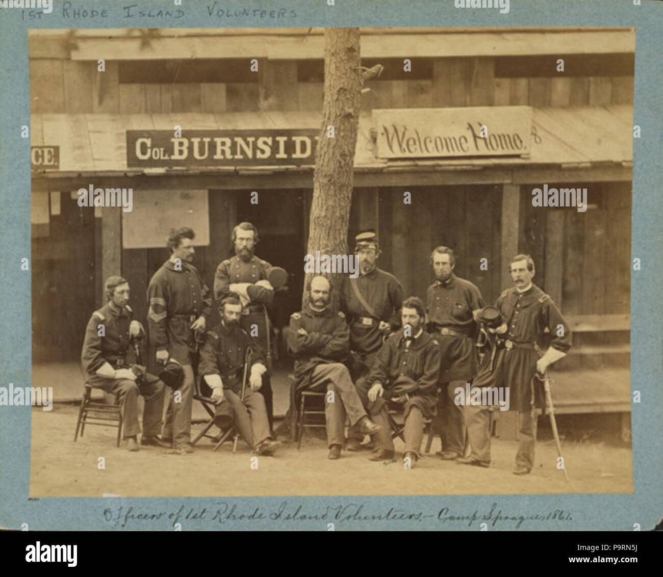 . English: Ambrose Everett Burnside with eight officers posed in front of building, with sign reading 'Col. Burnside welcome home.' Dansk: Officererne i 1. Rhode Island Volunteers 1861. photographed 1861, printed later 259 Burnside+1stRI Stock Photo