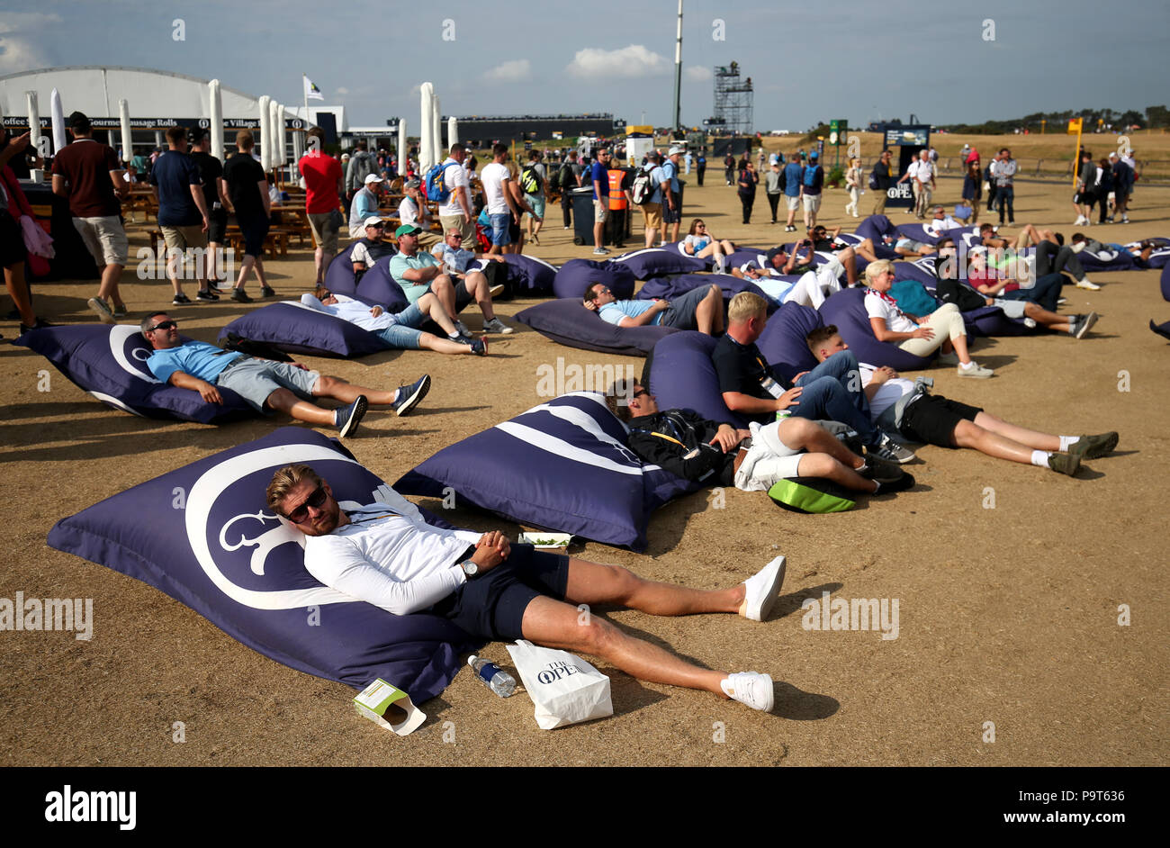 Spectators lay on giant bean bags watching the action on the big screen during day one of The Open Championship 2018 at Carnoustie Golf Links, Angus. Stock Photo