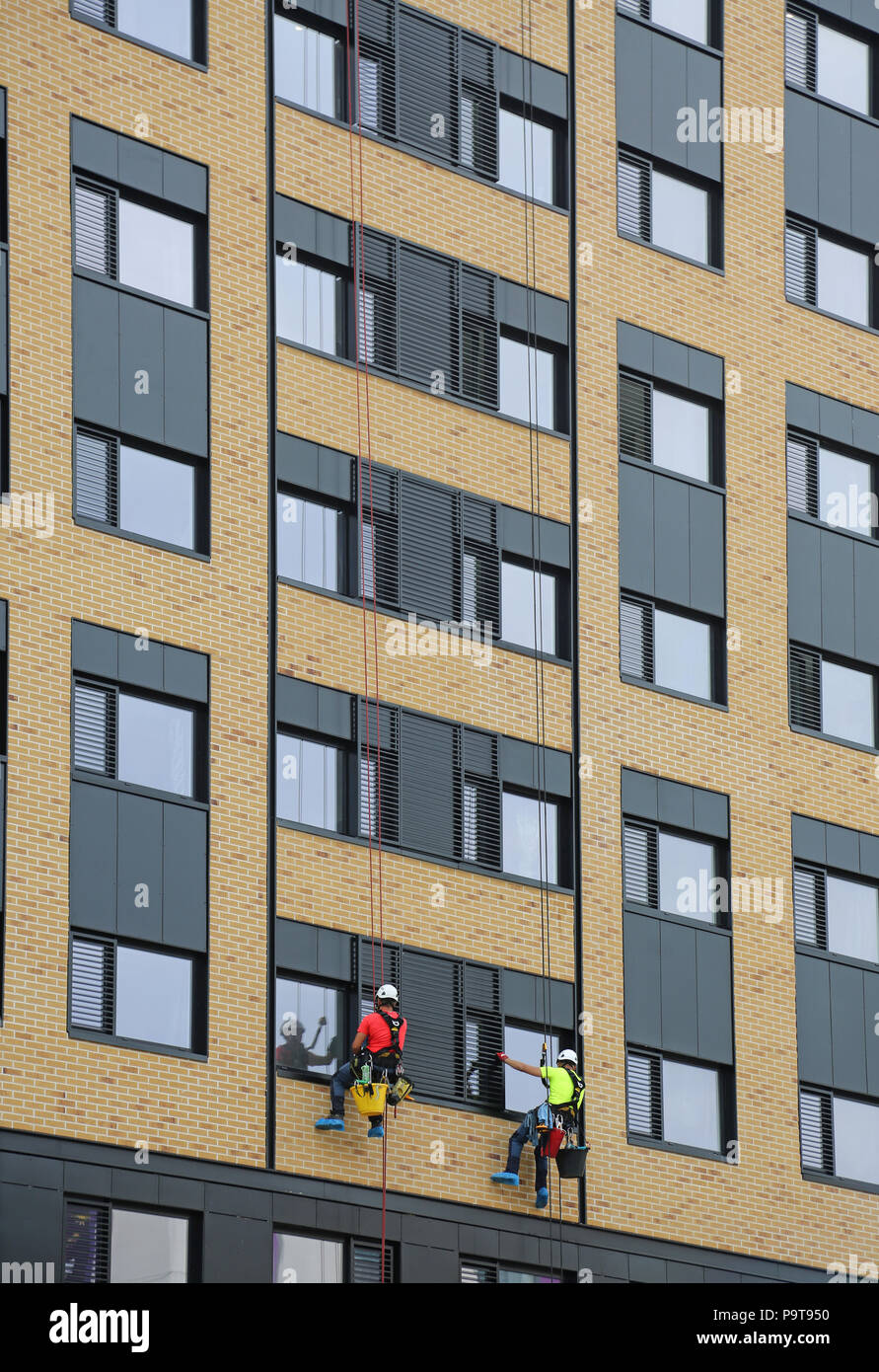 Two window cleaners use abseiling ropes to access windows on a new tower block in Portsmouth town centre, Hampshire, UK Stock Photo