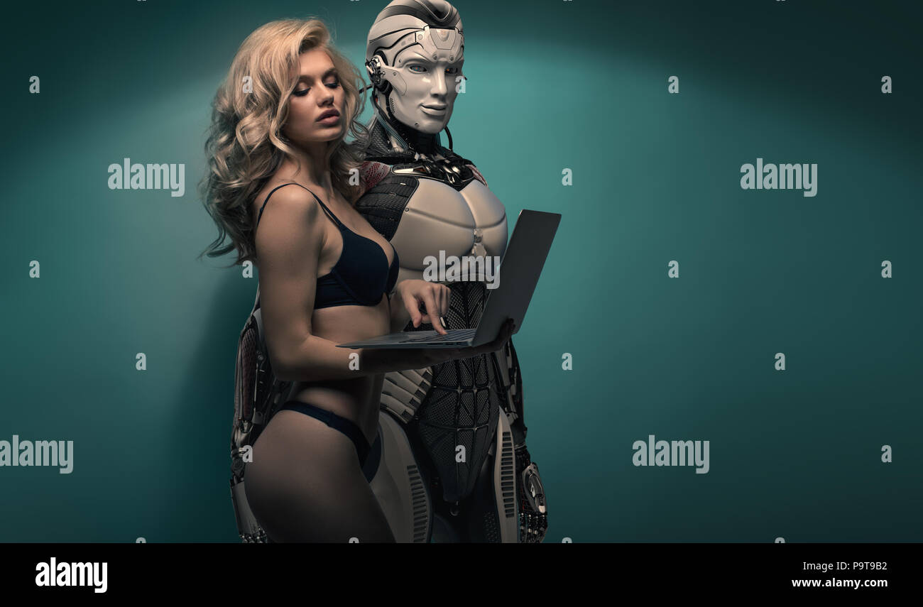 Attractive slender sexy blonde girl wearing black underwear holding laptop showing to a robotic man the screen, couple against bluish background Stock Photo picture