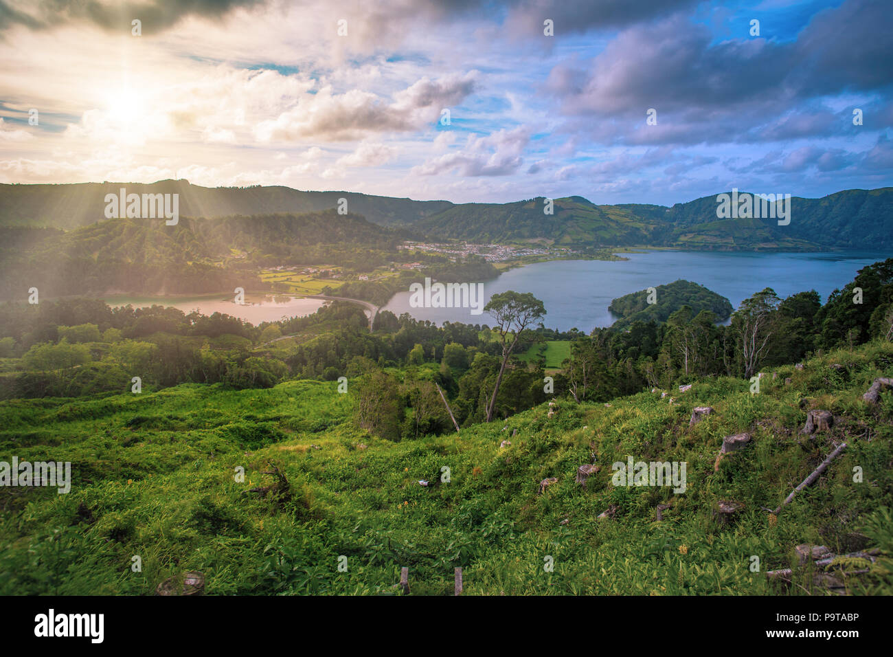 Beautiful sunset volcanic lake among mountains with green lush and trees in Ciete Cidades valley in Azores at San Miguel Island, sunlight and clouds o Stock Photo