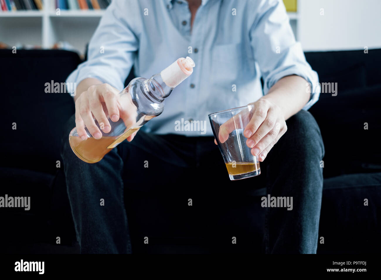Alcoholic man drinking and pouring hard liquor in the glass Stock Photo
