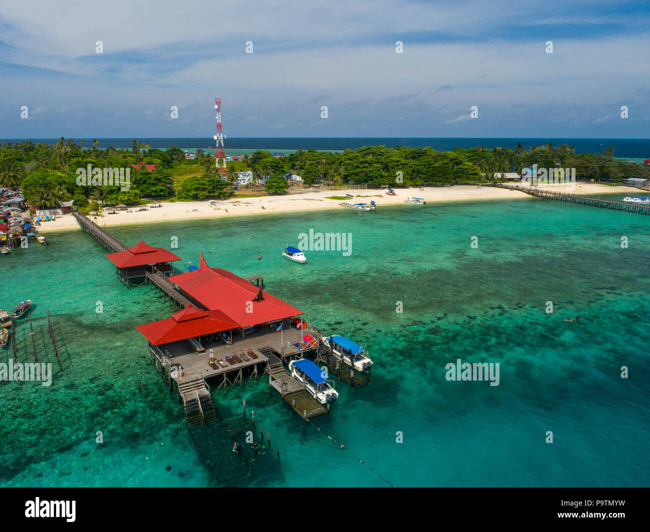 A drone photo of Scuba Junkie Mabul Beach Resort jetty, dive center, boats, coral reef, island and beach, at Mabul Island, Sabah, Malaysia (Borneo). Stock Photo