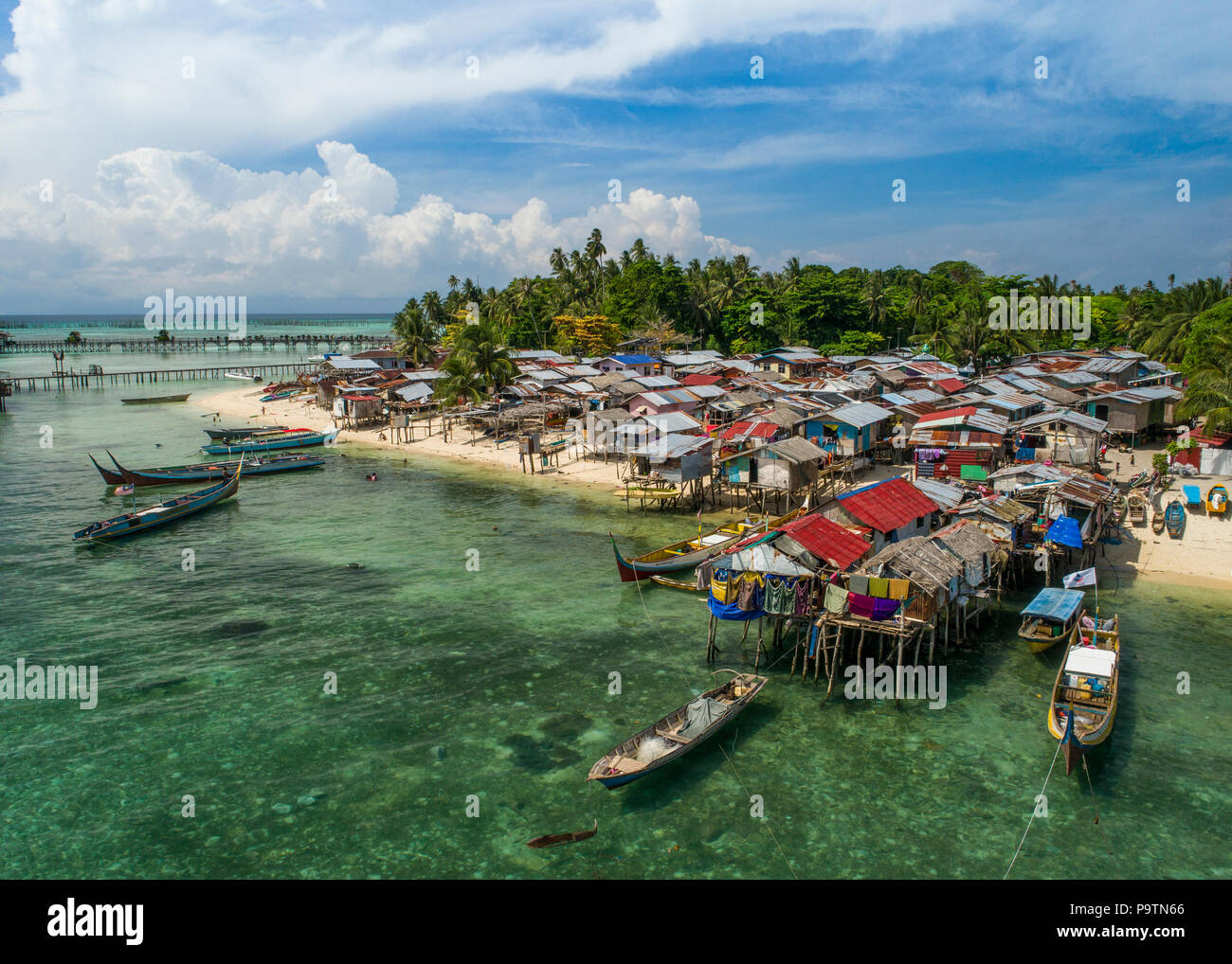 A drone photo of a very poor Bajau sea gypsy village on Mabul Island, Sabah, Malaysia (Borneo), with blue sky and clouds in the background. Stock Photo