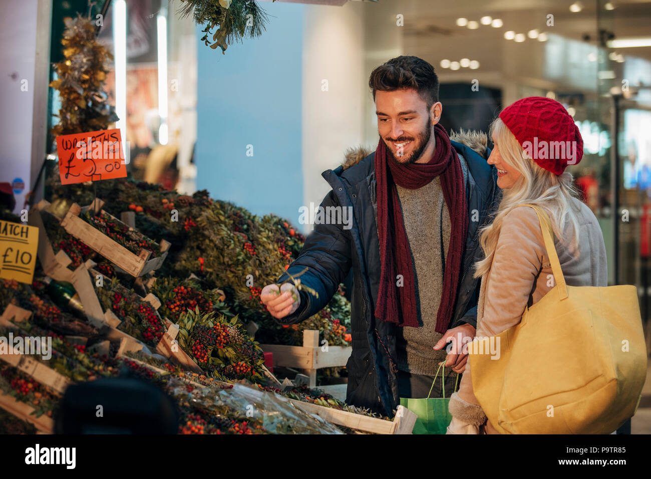 Side view of a couple deciding which wreath to buy. The wreat stall is on a city street market stall. Stock Photo