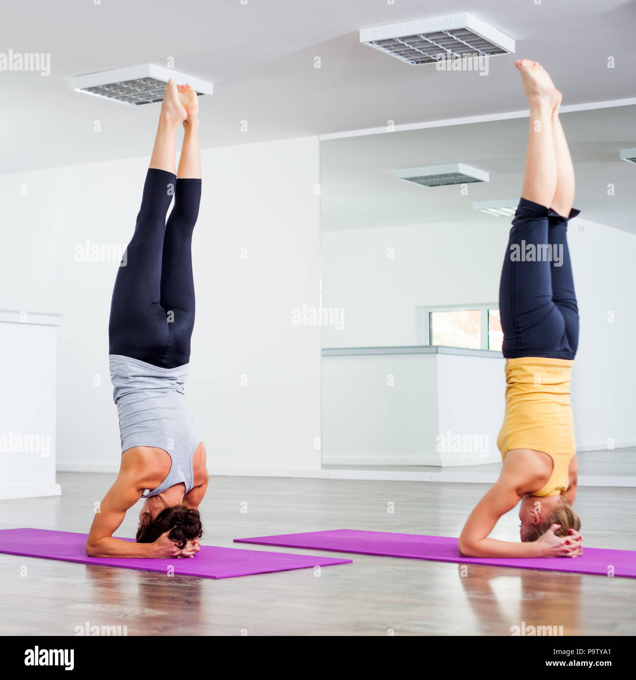 Two girls practicing yoga, Sirsasana / Headstand Stock Photo