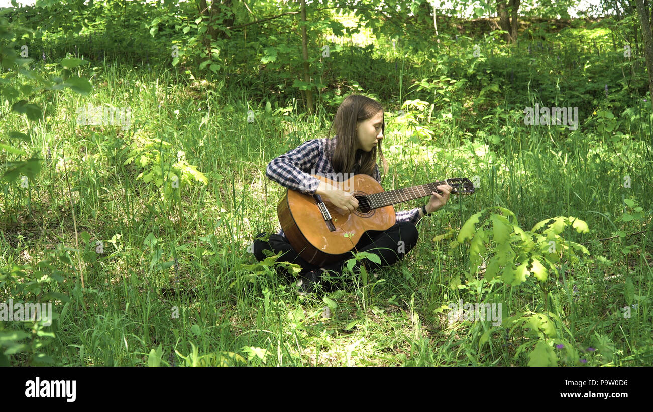 Young girl in forest with guitar in the garden. Teenage girl playing the  guitar in nature. Girl play solo guitar in green nature park Stock Photo -  Alamy