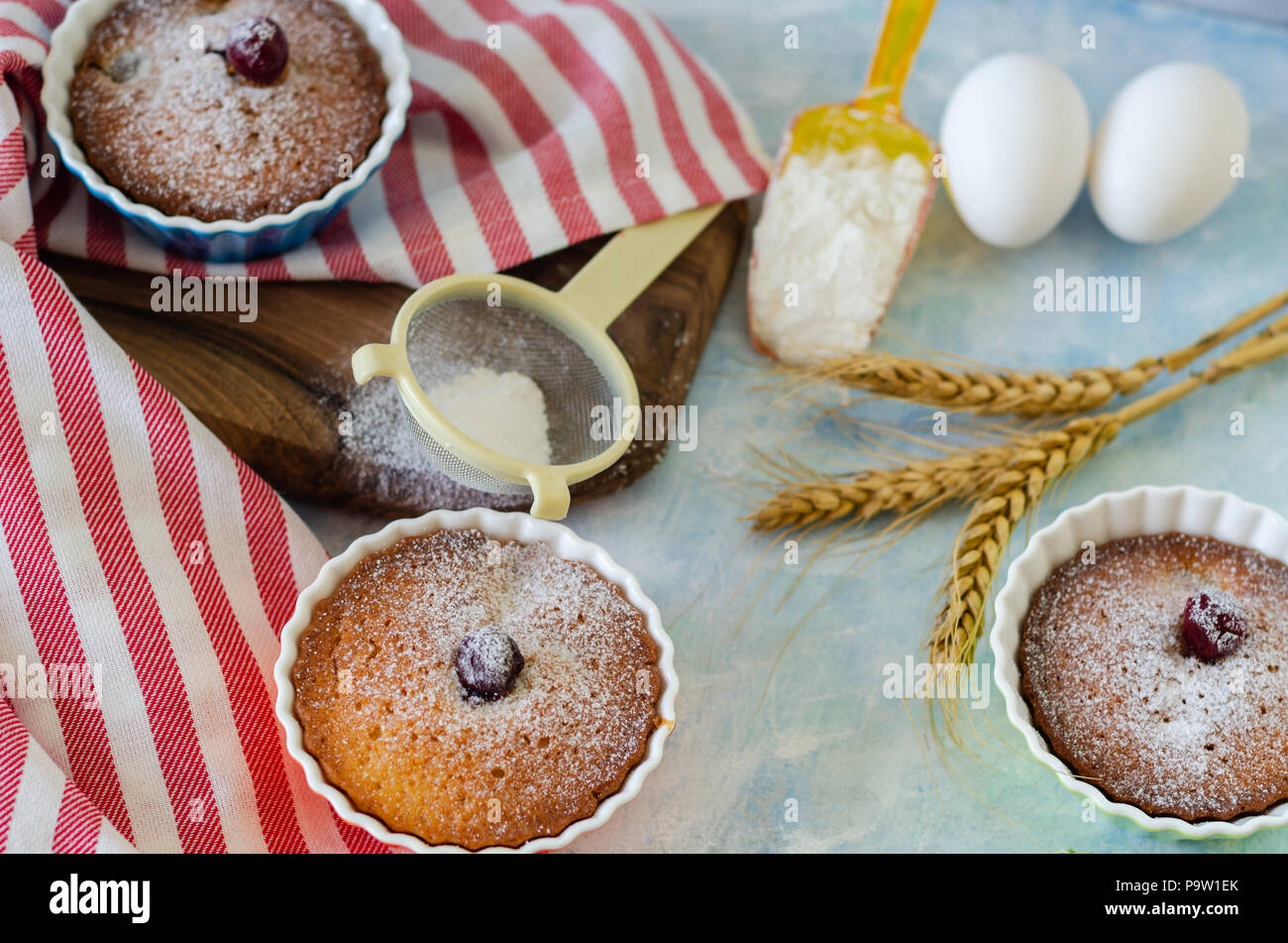 Cakes with cerries on a table in small porcelain cups .There are eggs