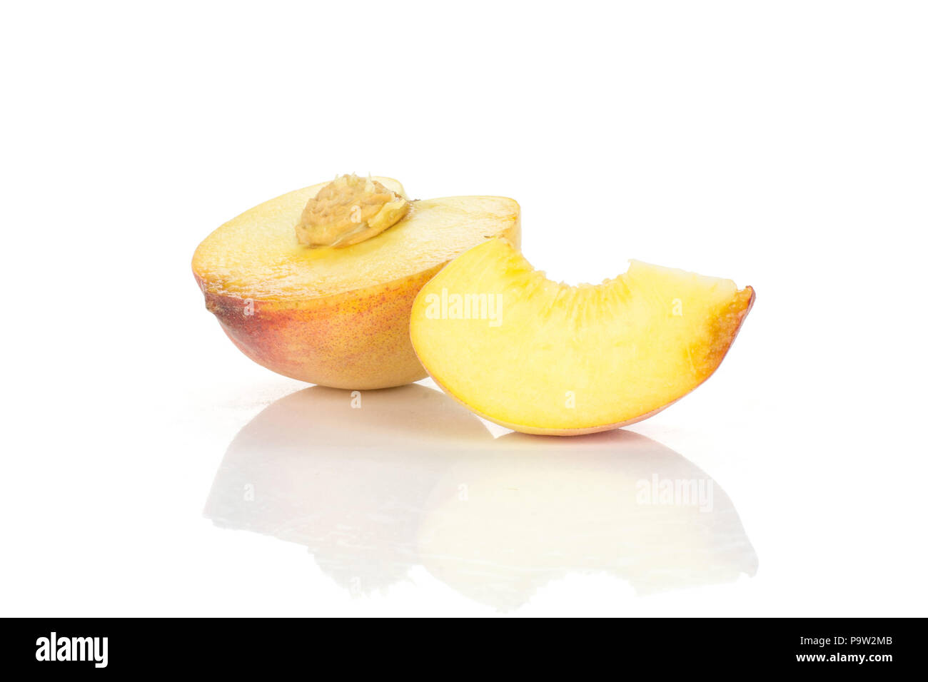 One yellow peach half with a slice and drupe inside isolated on white background Stock Photo
