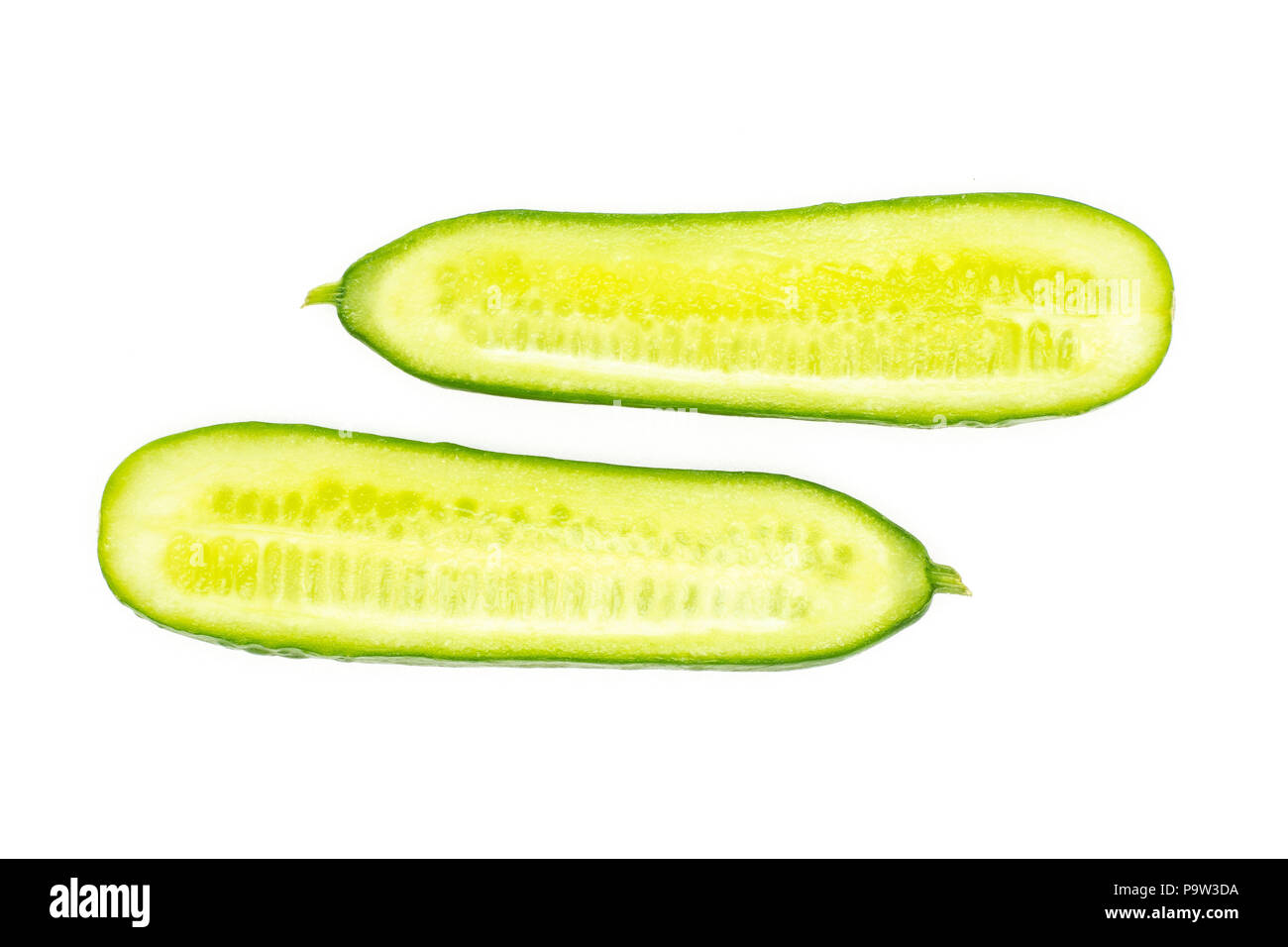 Two fresh mini cucumbers section halves flatlay isolated on white background Stock Photo
