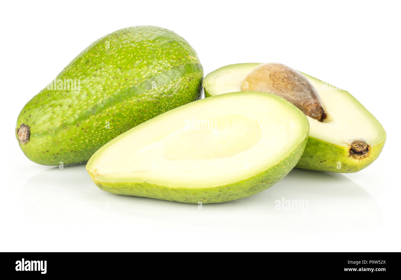 Sliced green smooth avocado one whole and two halves with a brown seed isolated on white background bacon variety Stock Photo