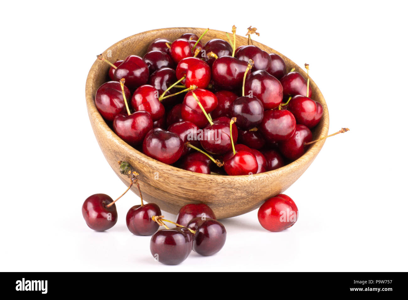 Sweet bright red cherry in a wooden bowl and near it isolated on white Stock Photo