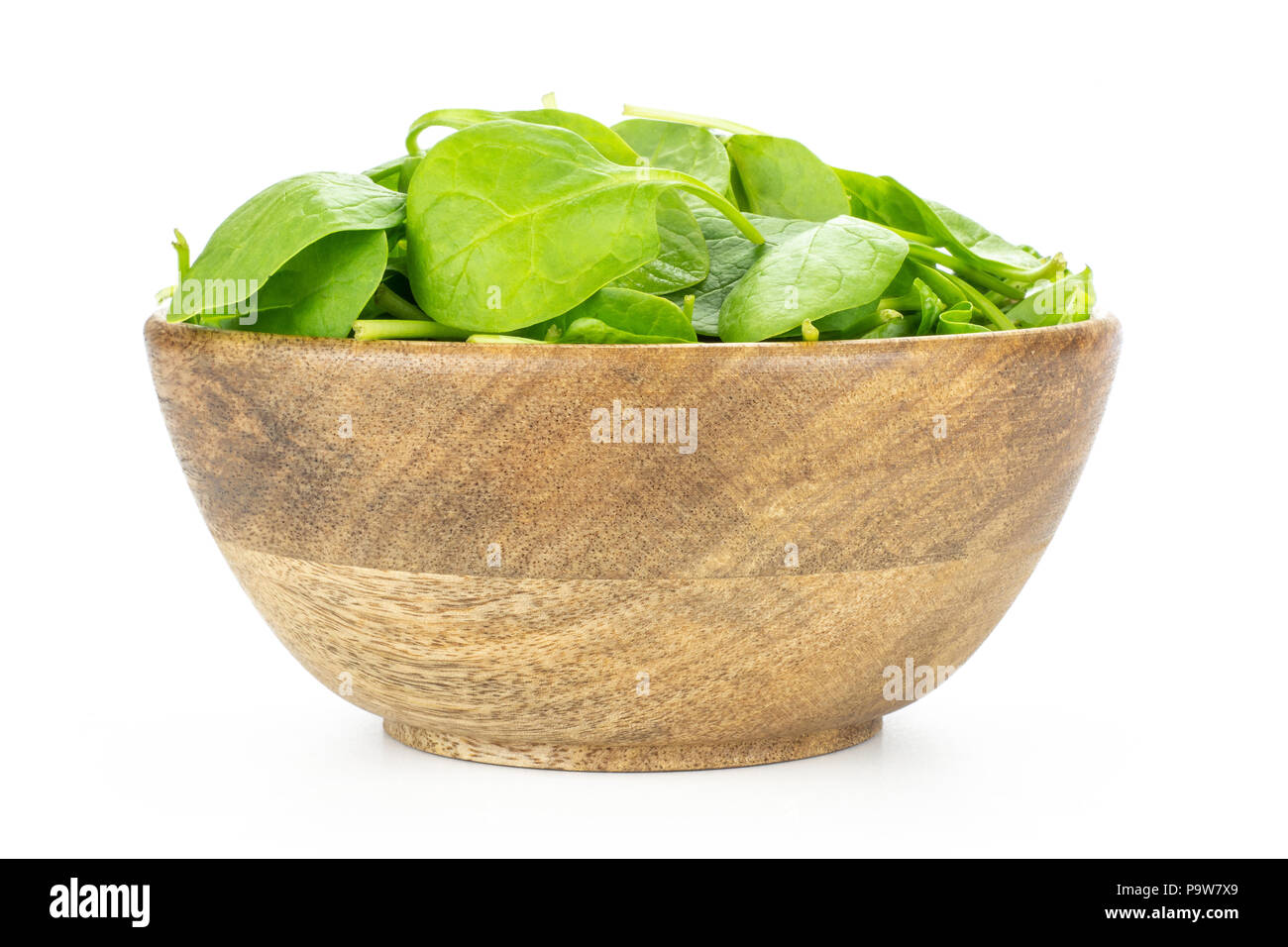 Fresh baby spinach leaves in a wooden bowl isolated on white background Stock Photo