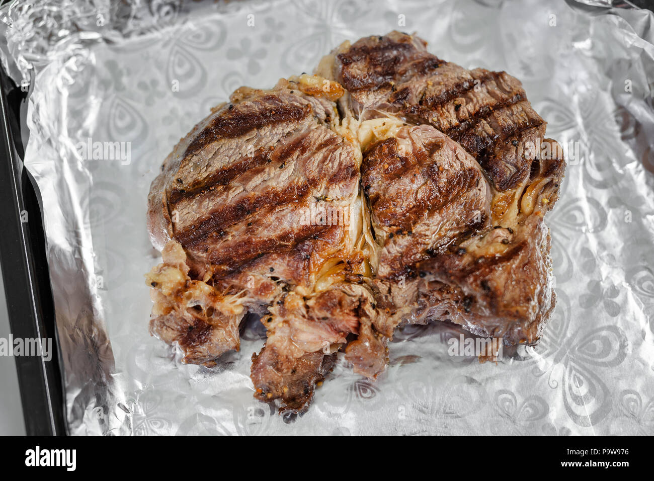 Closeup tasty juicy rib eye steak on aluminium foil. . Organic beef meat seasoned with ground