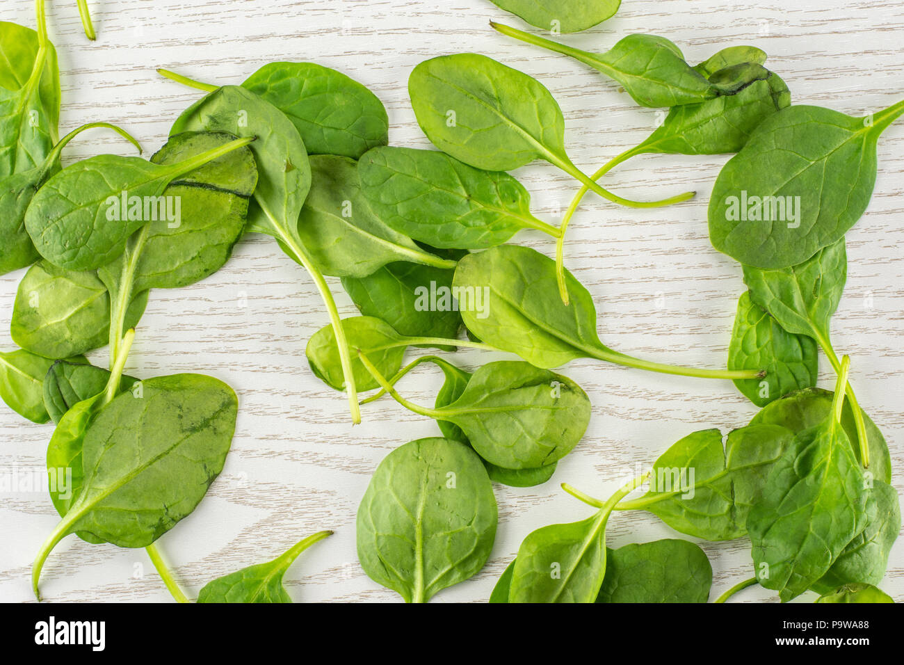 Fresh baby spinach leaves top view on grey wood background Stock Photo