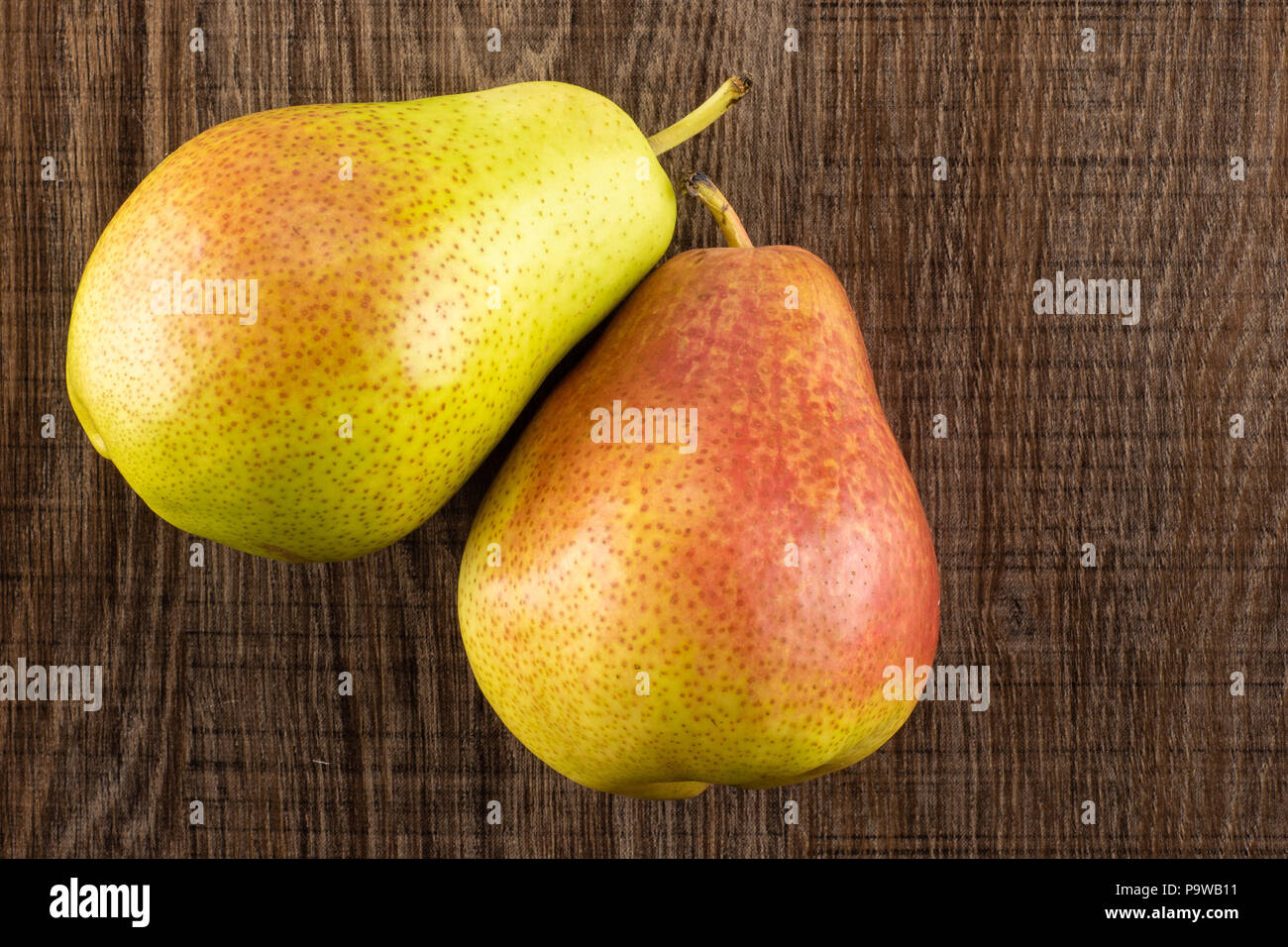 Group of two whole fresh red pear forelle variety flatlay on brown wood Stock Photo