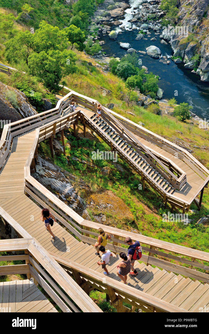 People stepping down wooden staircase towards  green and rocky river canyon Stock Photo