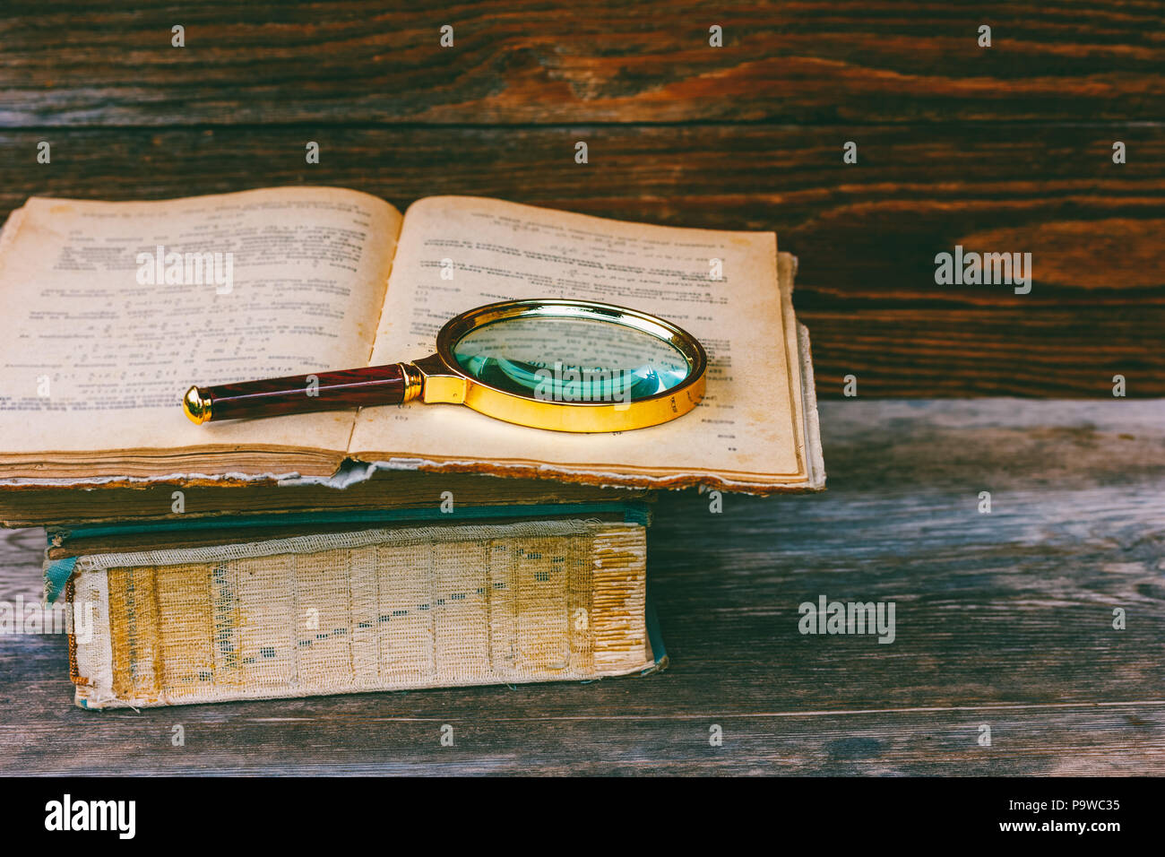 magnifying glass on old open book closeup Stock Photo - Alamy