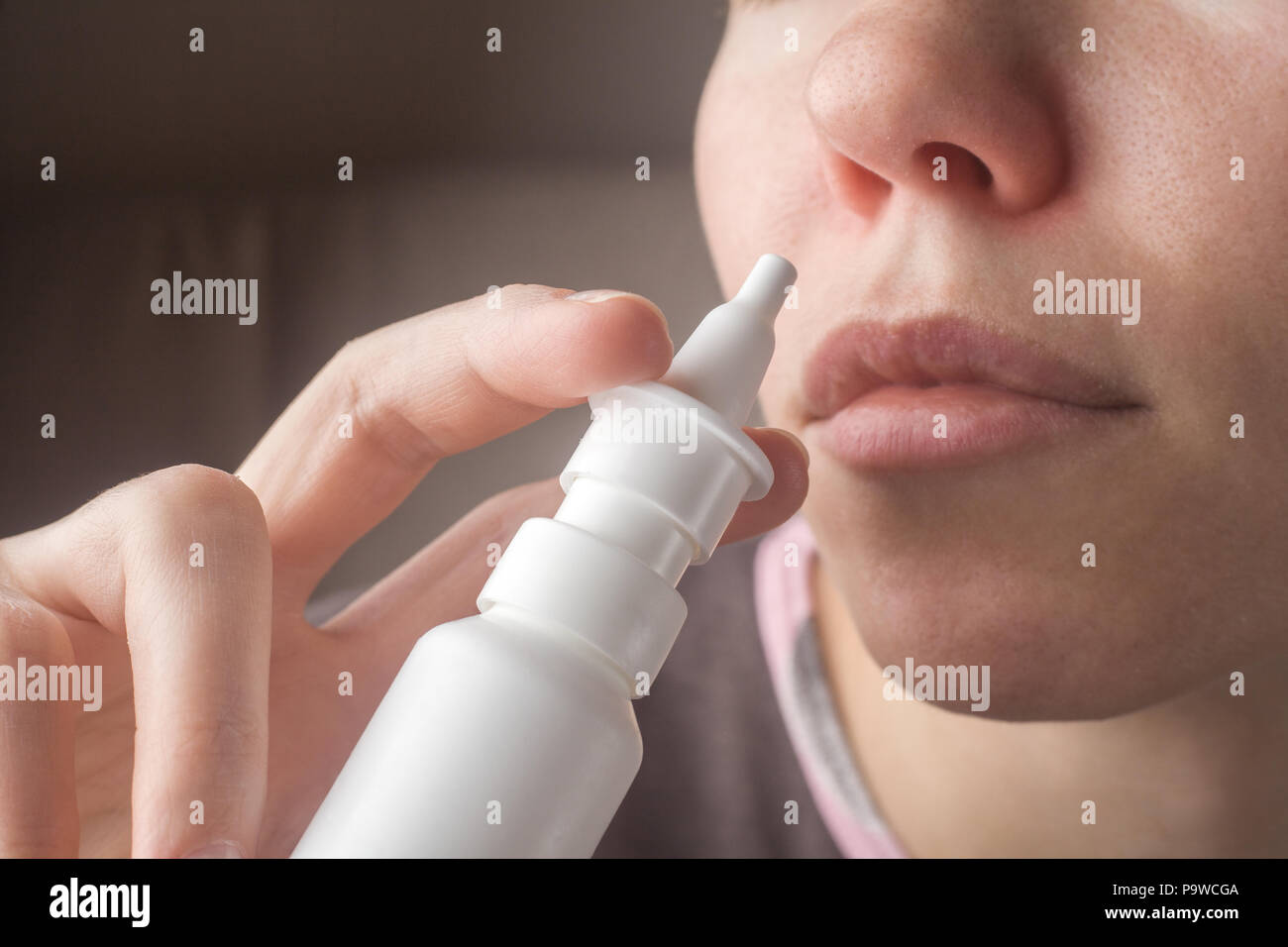 A woman with a runny nose holds a medicine in her hand, a red no Stock Photo
