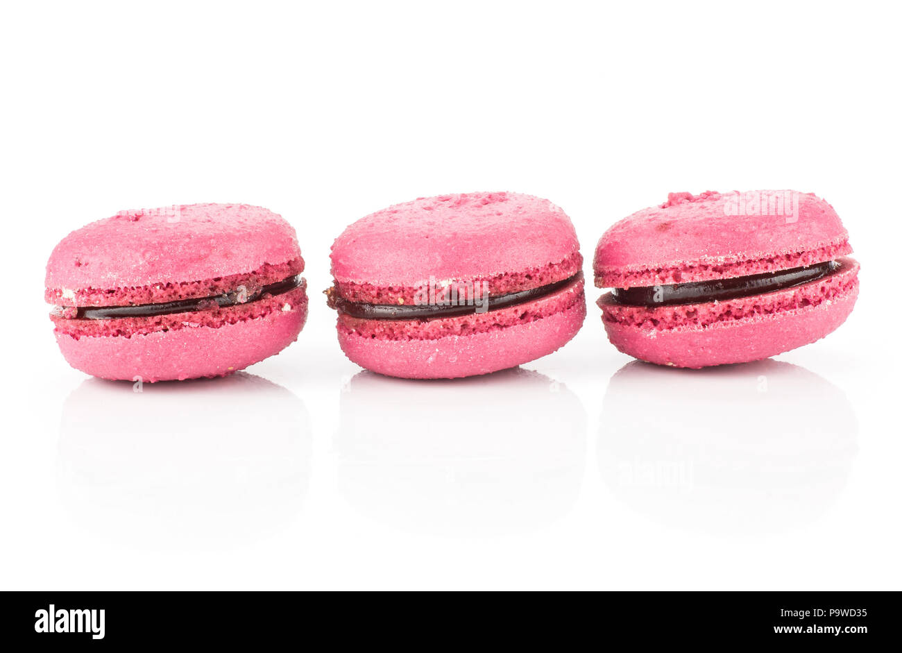 Pink French macarons three with raspberry jam in row isolated on white background Stock Photo