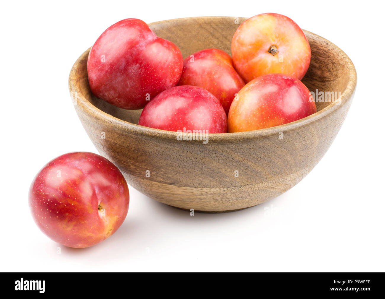 Plums red orange in a wood bowl isolated on white background Stock Photo
