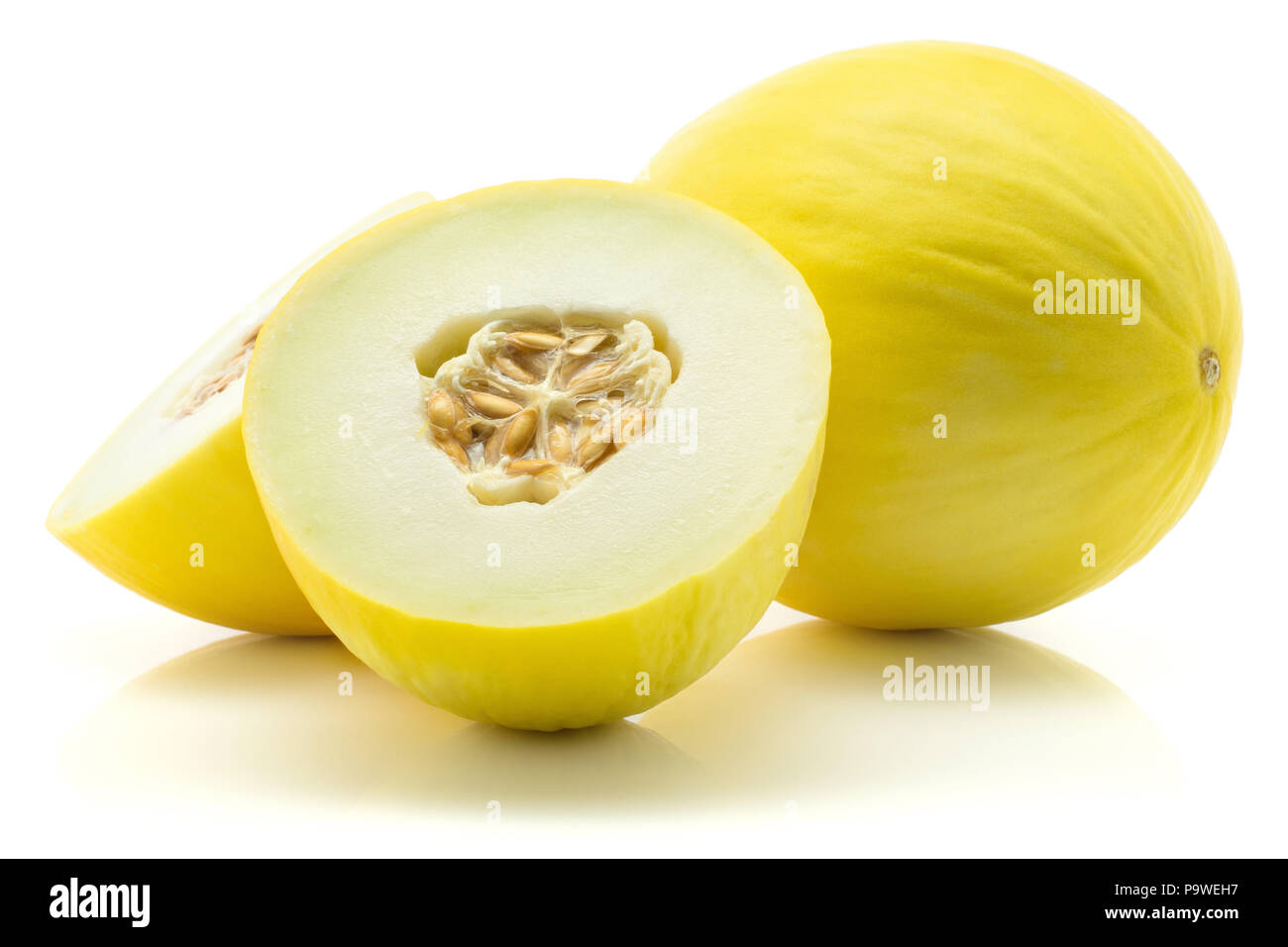 Yellow honeydew melon set, one cut in half and one whole, isolated on white background, two halves with seeds Stock Photo