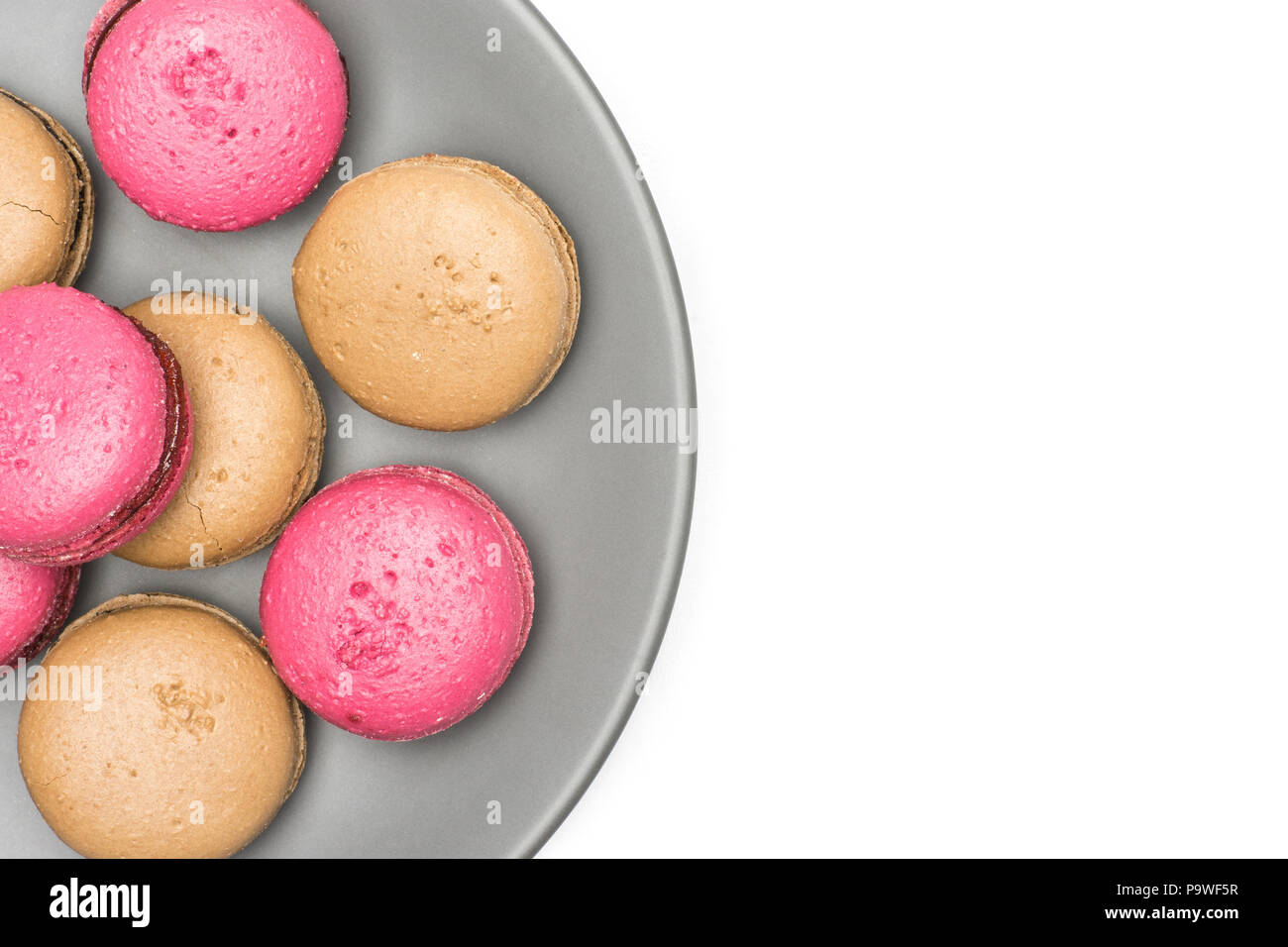 French macarons (chocolate, raspberry) on a grey plate top view isolated on white background Stock Photo