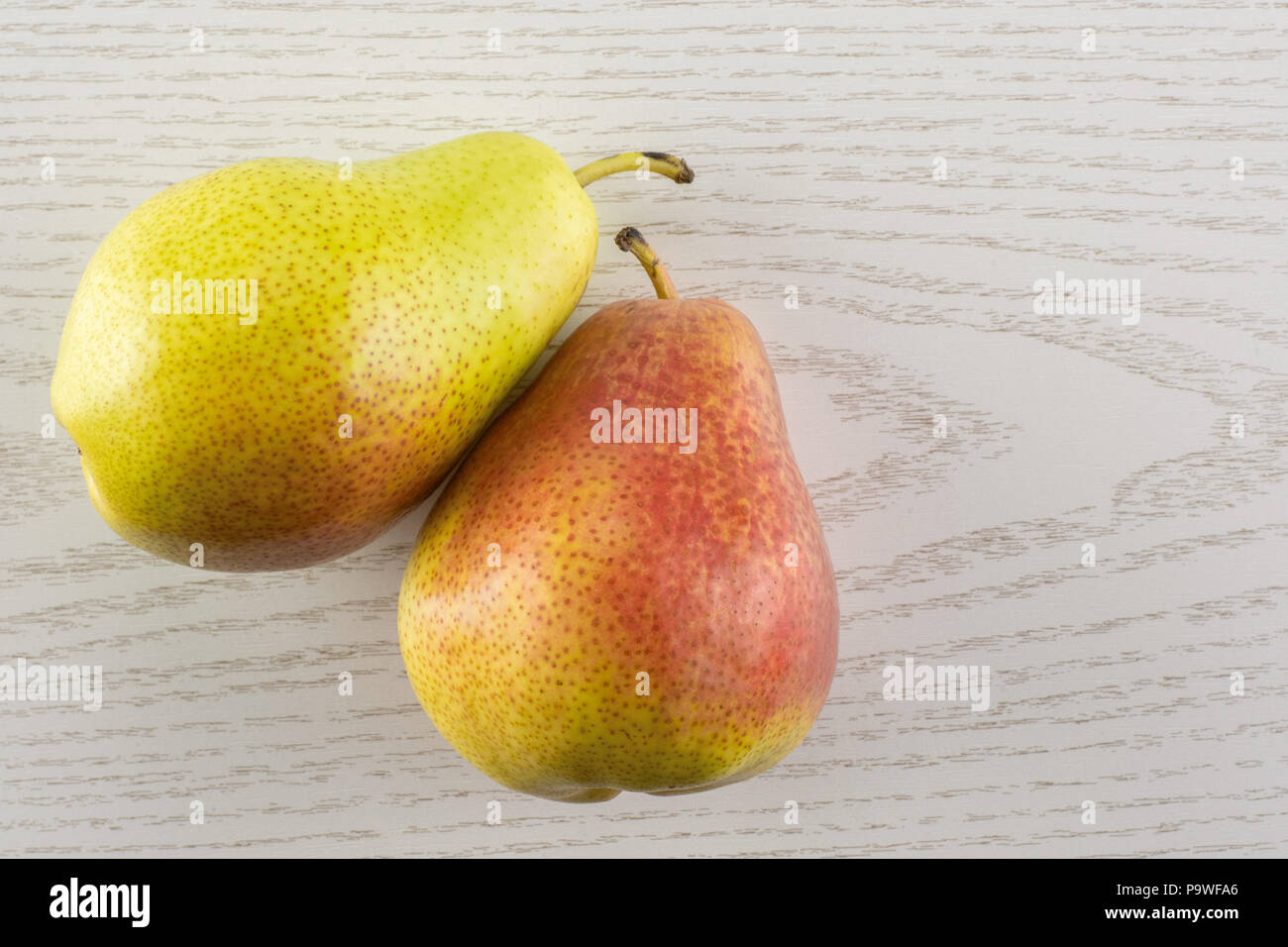 Group of two whole fresh red pear forelle variety flatlay on grey wood Stock Photo