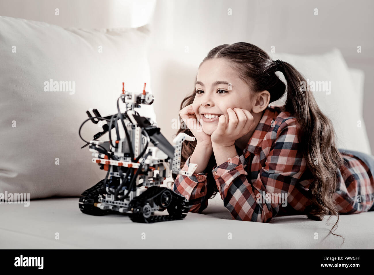 Stunning robot. Charming nice smart girl crazy about her lying on the couch hands under her chin Stock Photo - Alamy