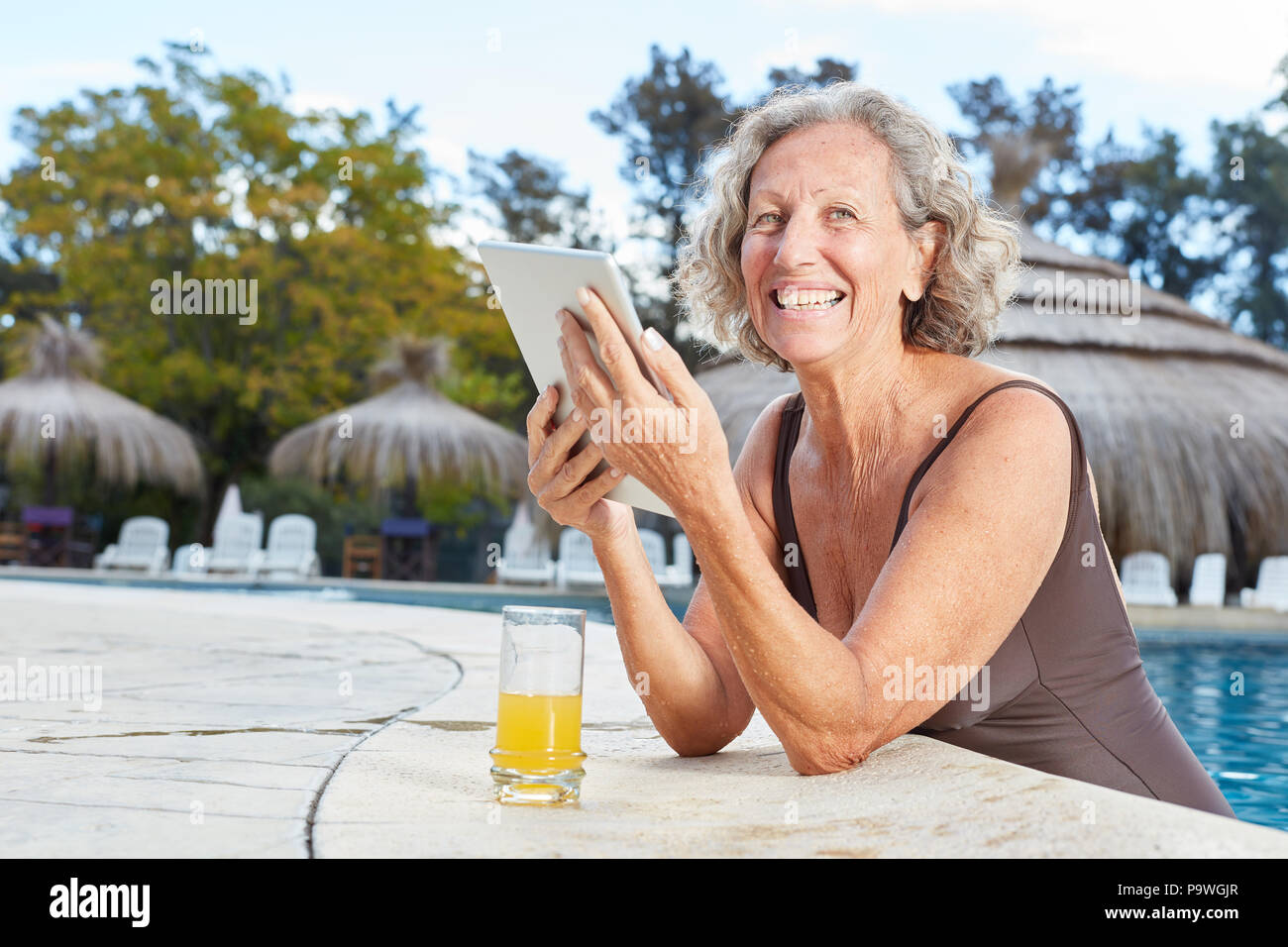 Happy woman using tablet computer in spa pool during wellness vacation Stock Photo