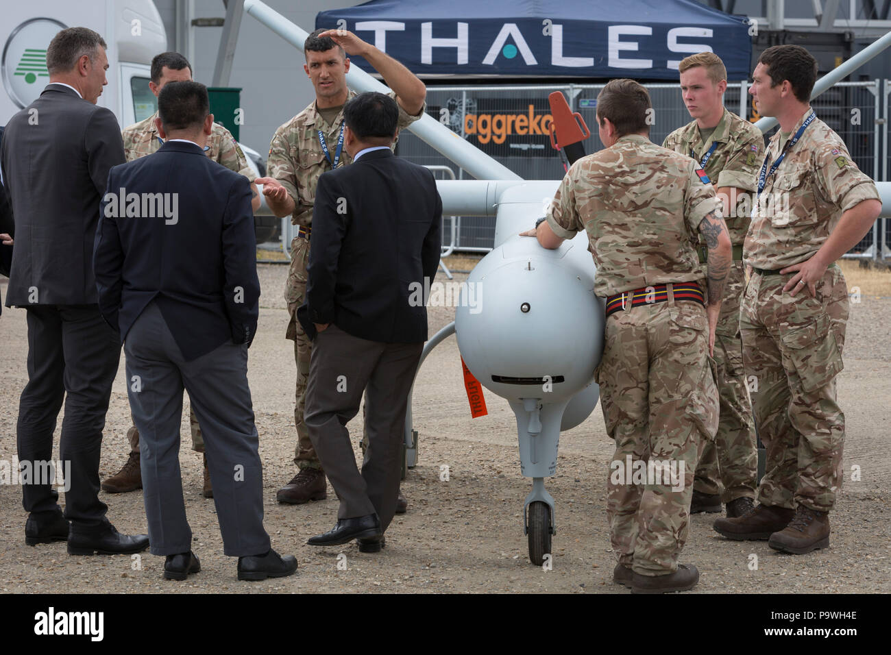 A foreign delegation listens to a briefing by a member of the British Army's Royal Artillery, demonstrating a Thales Watchkeeper UAV at the Farnborough Airshow, on 18th July 2018, in Farnborough, England. Stock Photo