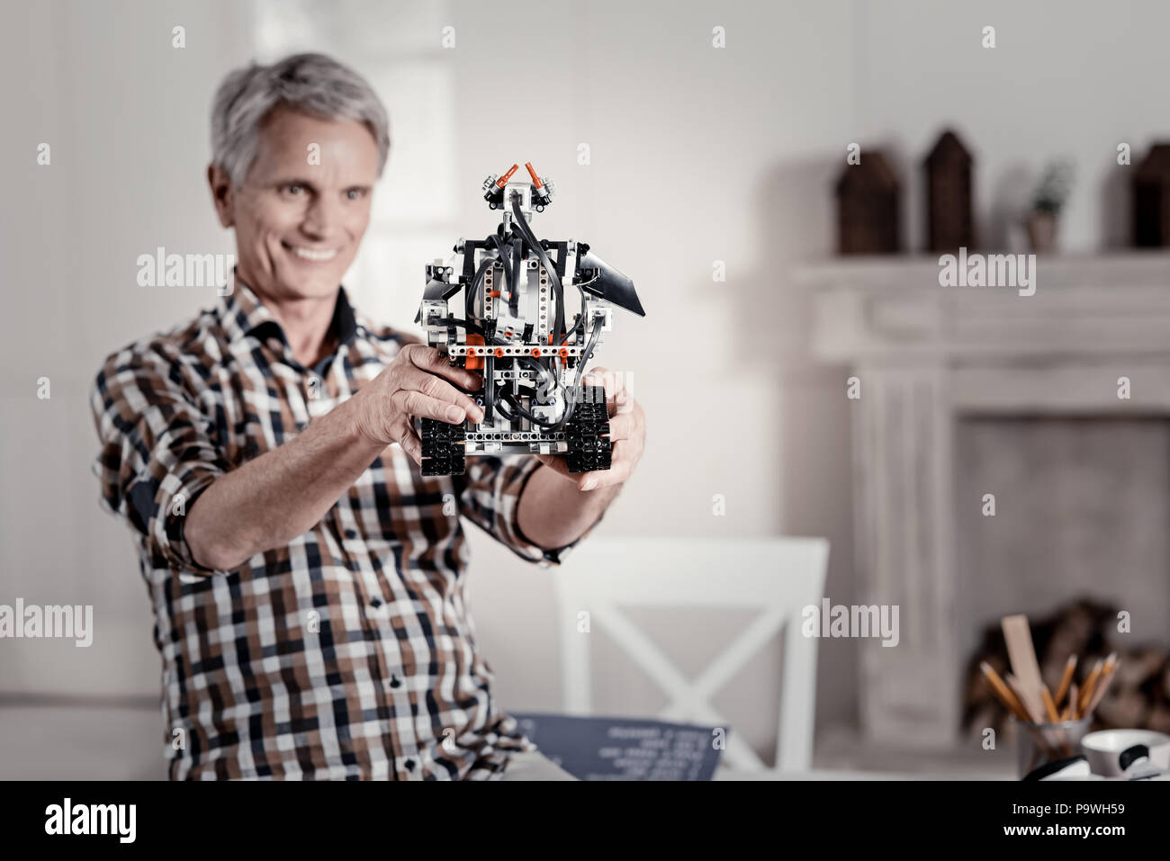 Total perfection. Grinning mature man holding perfect detailed robot which turned back to the camera Stock Photo