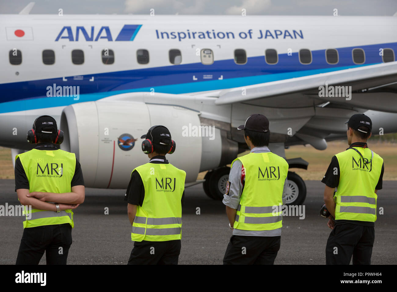 Ground crew with the Japanese airliner manufacturer, Mitsubishi wait for their MRJ (Mitsubishi Regional Jet) with the airline ANA to take off for its fliying demonstration at the Farnborough Airshow, on 18th July 2018, in Farnborough, England. Stock Photo