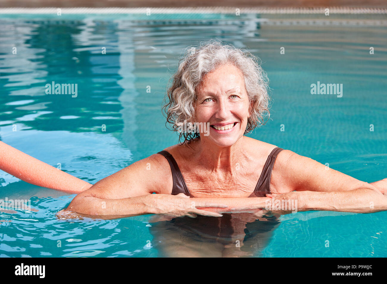 Smiling Senior Woman Is Doing Aqua Fitness With A Swimming Aid In The