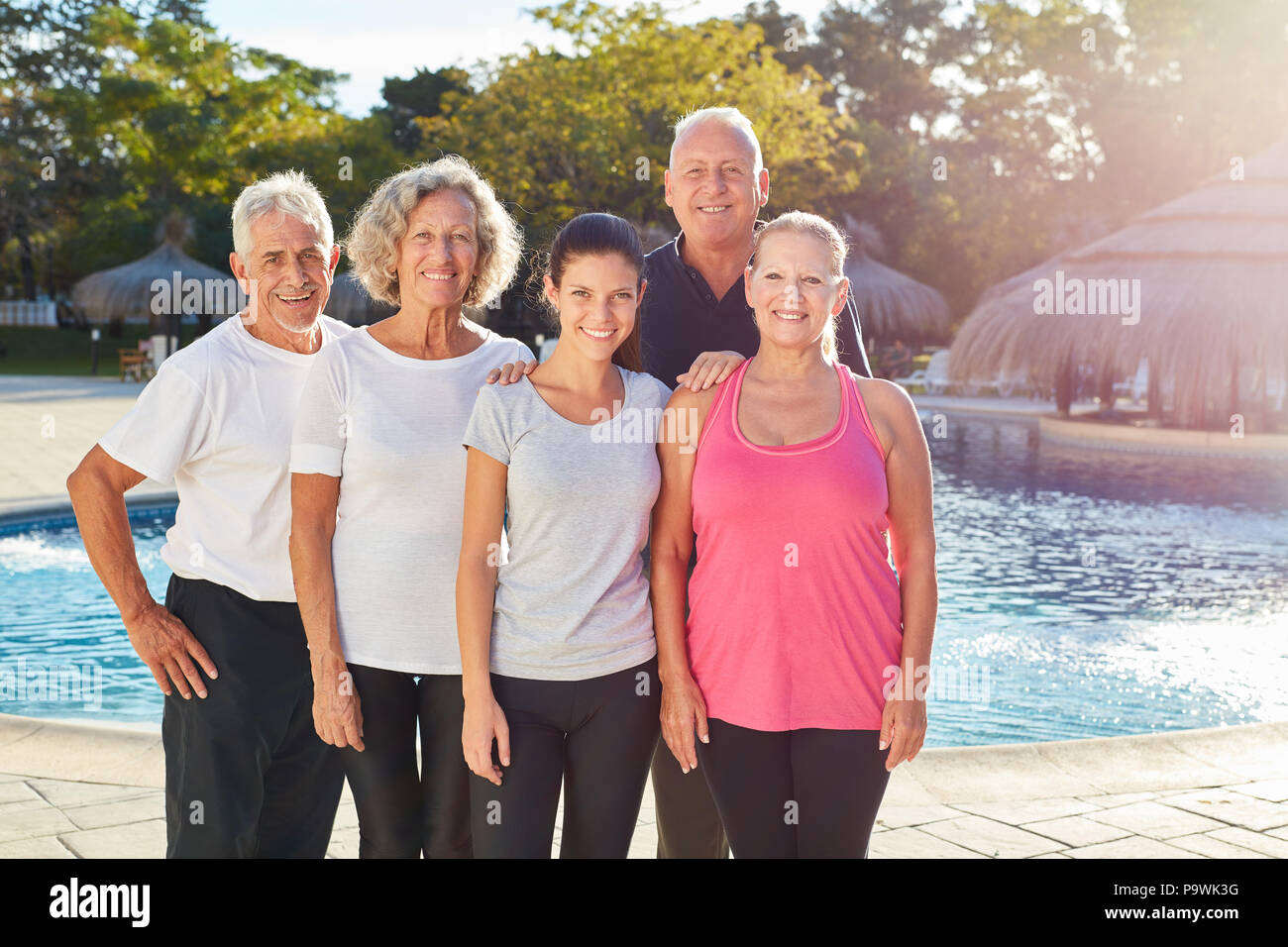 Senior group is standing by the swimming pool at the spa hotel during summer vacation Stock Photo