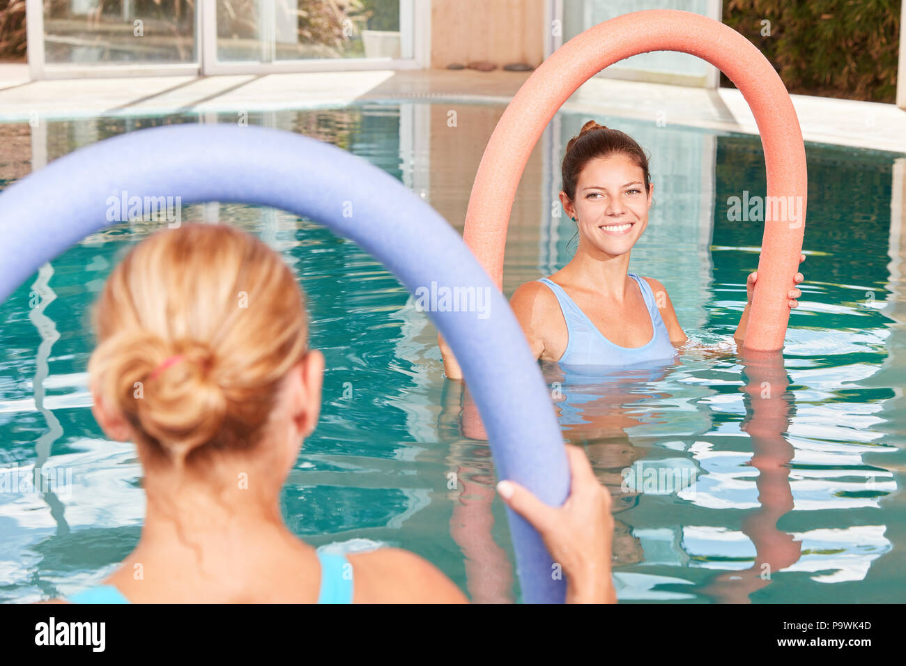 Woman as a trainer in an aqua gym Course with swimming noodle in the pool Stock Photo