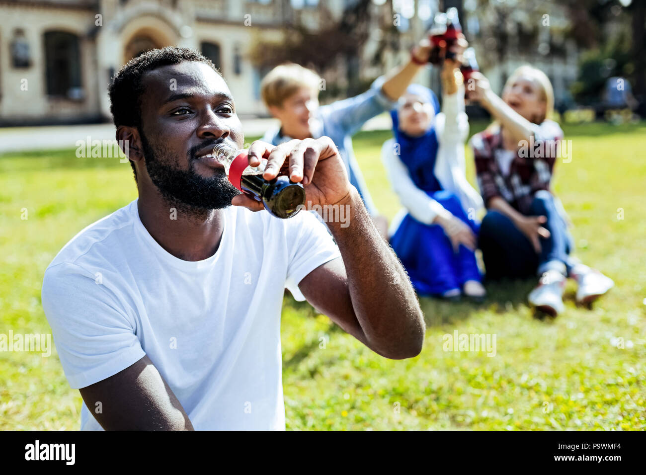 Cheerful guy smiling while drinking soda outdoors Stock Photo - Alamy