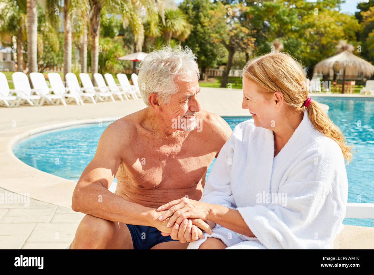 Happy senior couple in love sitting by the pool on a spa vacation Stock ...