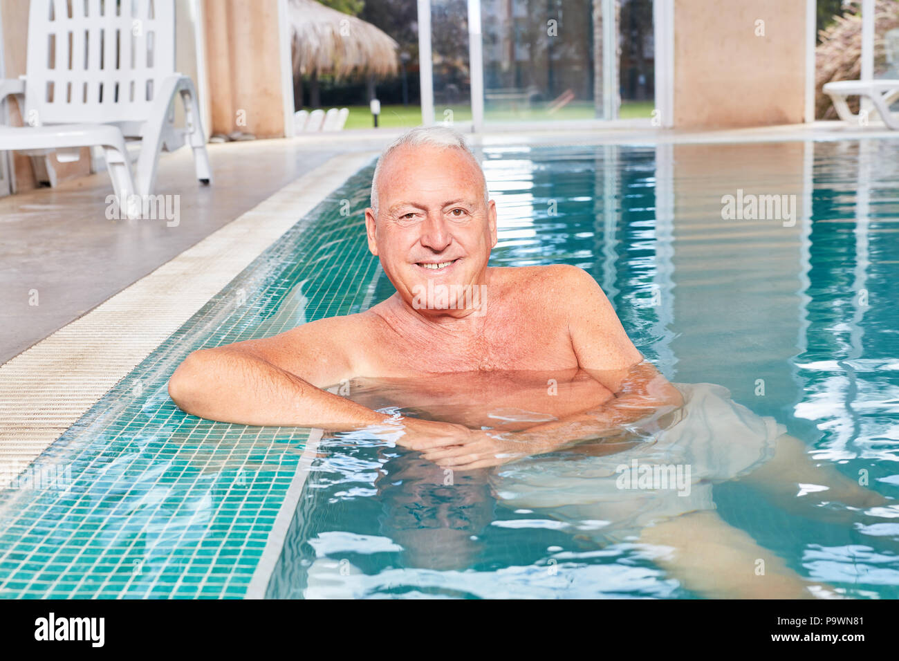 Smiling senior man as a vital retiree in the swimming pool at leisure Stock Photo