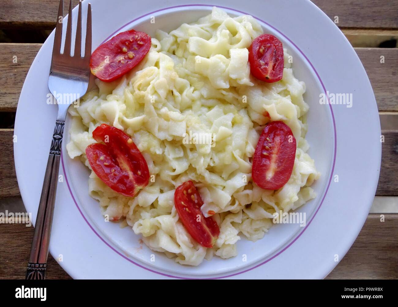 Greek Traditional Pasta Hilopites Kontes with grated cheese and cherry tomatoes Stock Photo