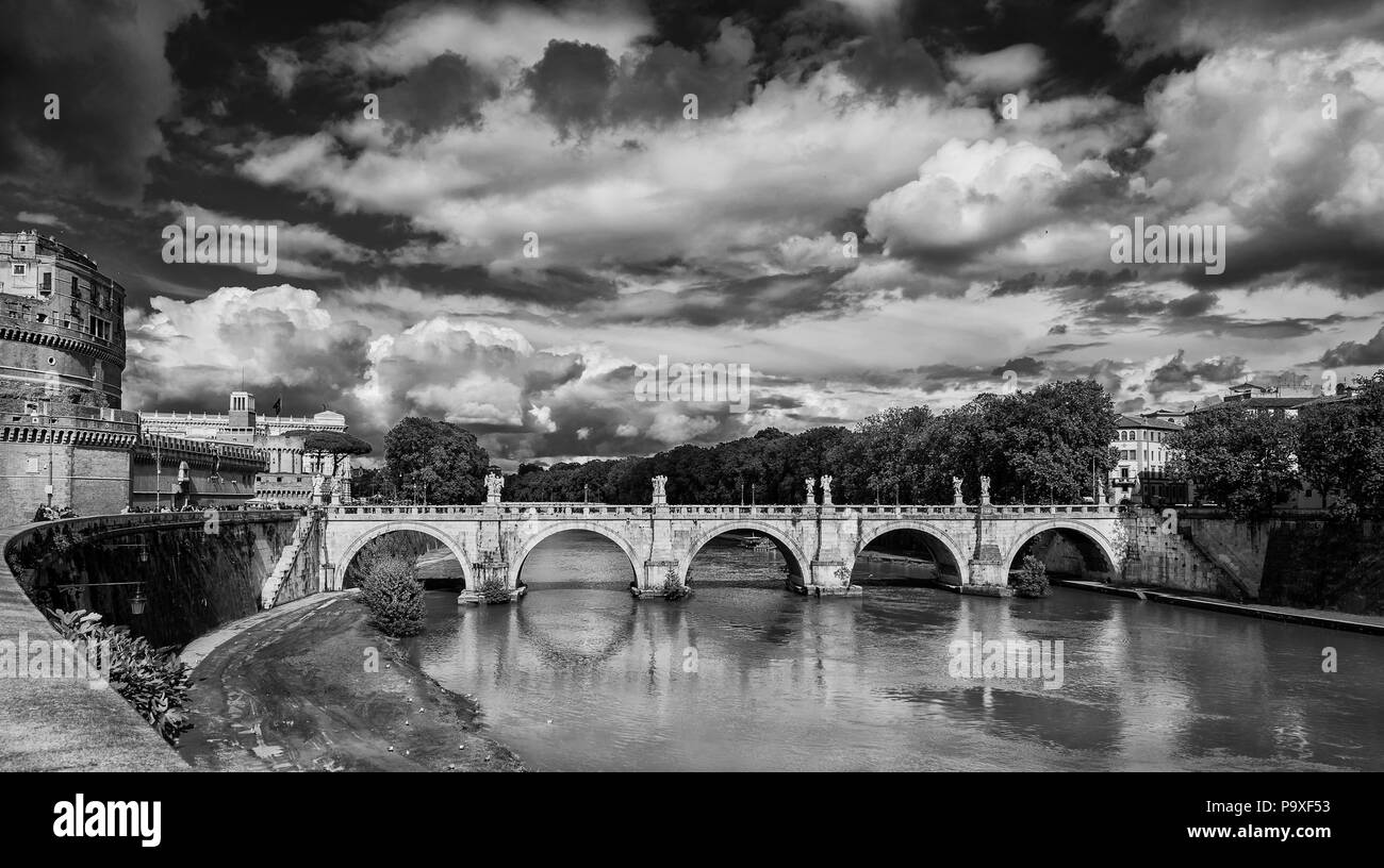 Panoramic view of River Tiber with the Holy Angel Bridge, erected in the 17th century, and beautiful clouds in Rome (Black and White) Stock Photo
