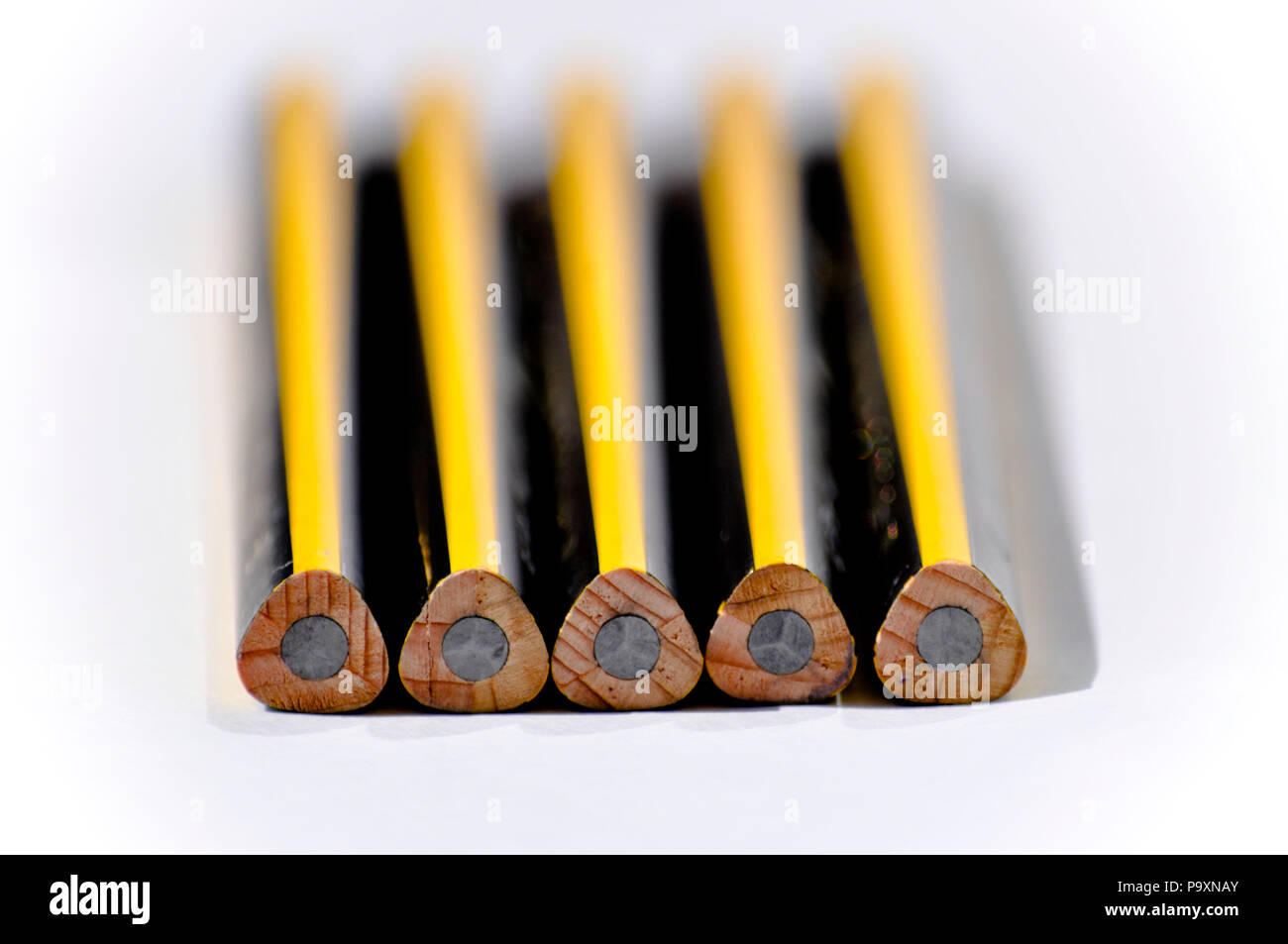 Five new triangular HB pencils with blunt ends set against a white background Stock Photo