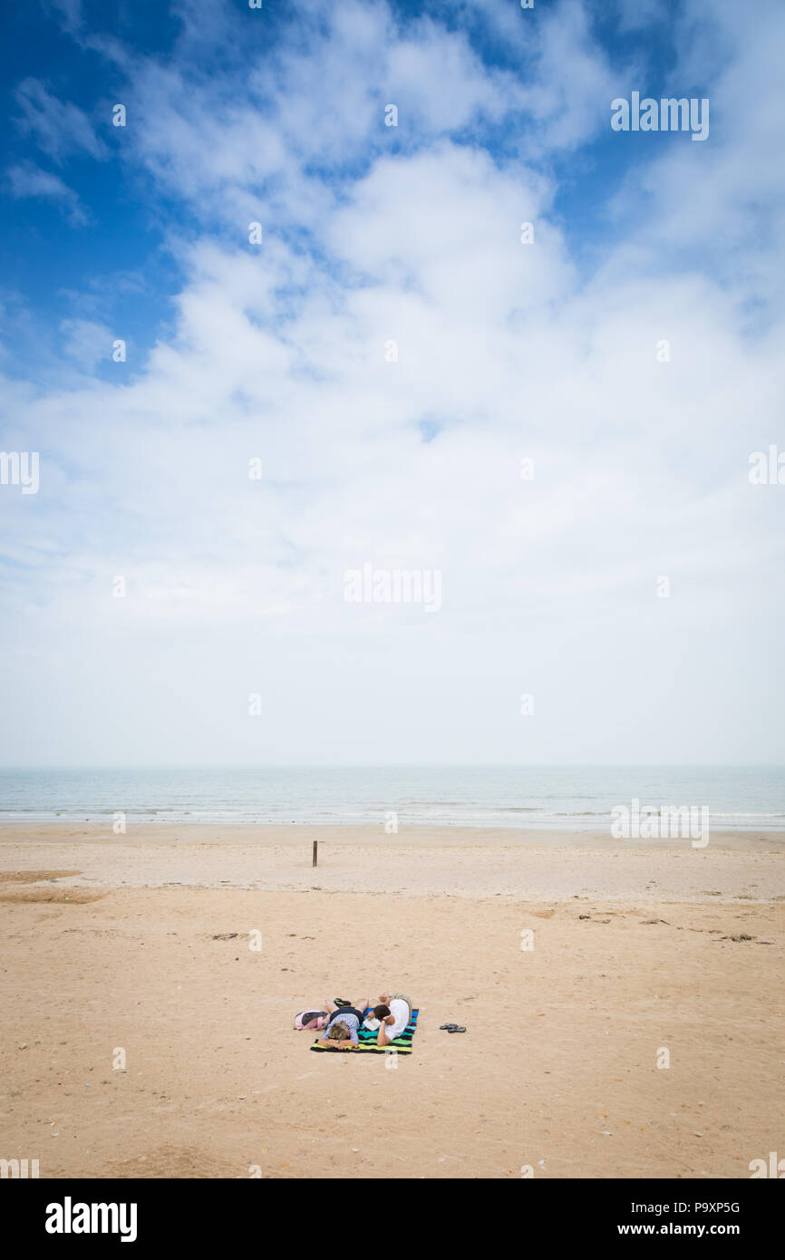 Two people sunbathing on an wide empty beach, Normandy, France Stock Photo