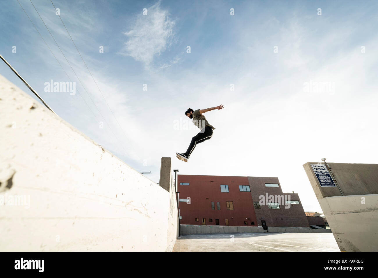 Side view of single male parkour athlete jumping from one wall to another Stock Photo